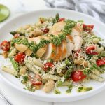 A plate of Gluten -Free Chicken Basil Pesto Pasta with a fork, gray and white striped napkin