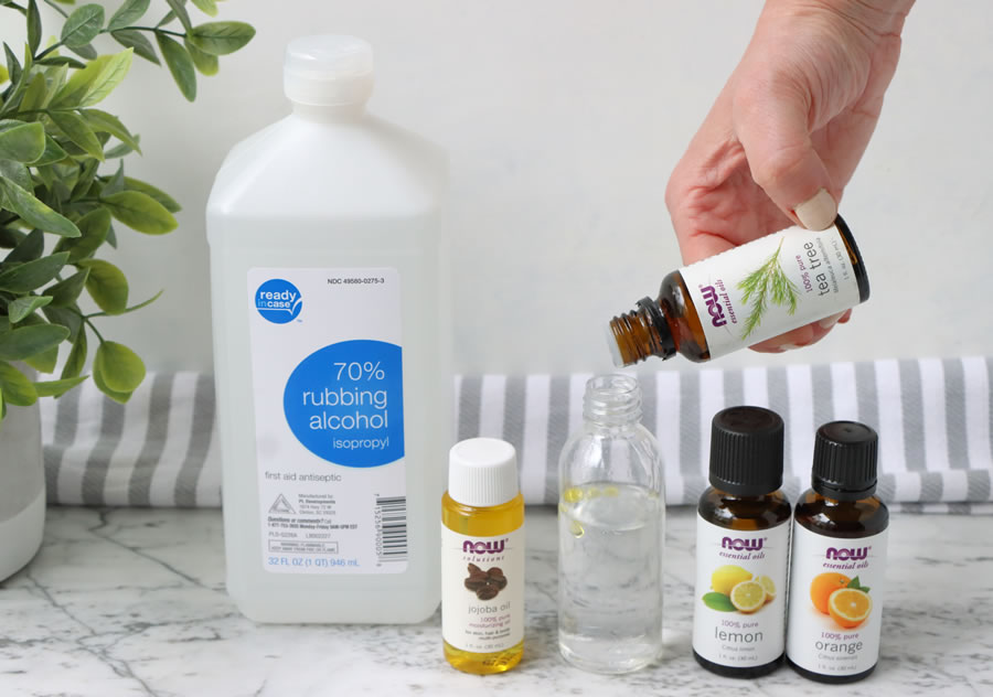 pouring tea tree oil into 70% rubbing oil to make hand sanitizer at home