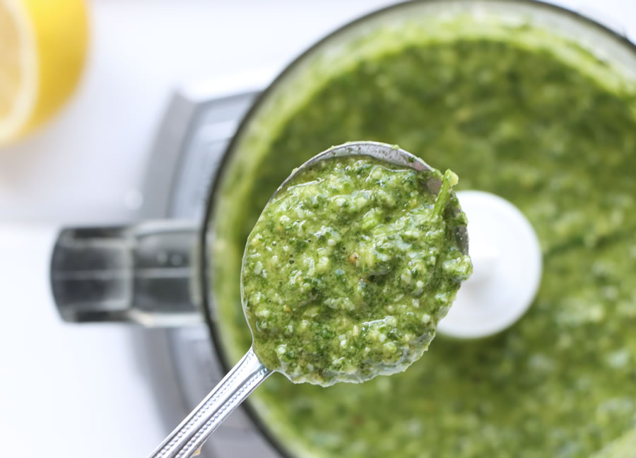 homemade an overhead of a spoonful of basil pesto over a food processor