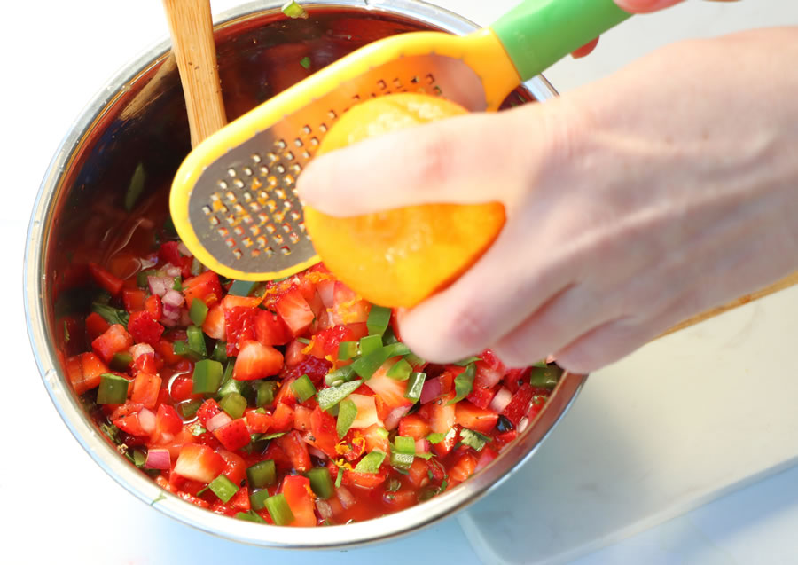 grating orange zest over strawberry salsa