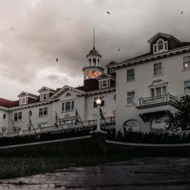 a spooky image of the haunted stanley hotel. a cloudy dusky eve with crows flying above