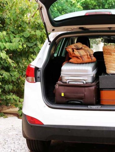 an suv from the rear, back hatch open filled with luggage on a summer day.