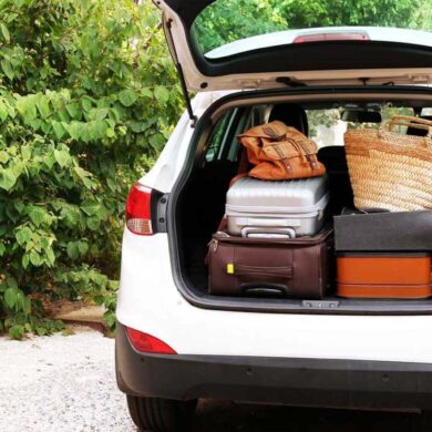 an suv from the rear, back hatch open filled with luggage on a summer day.