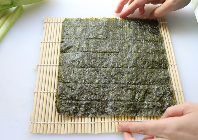 a seaweed nori sheet on a bamboo rolling mat for making sushi