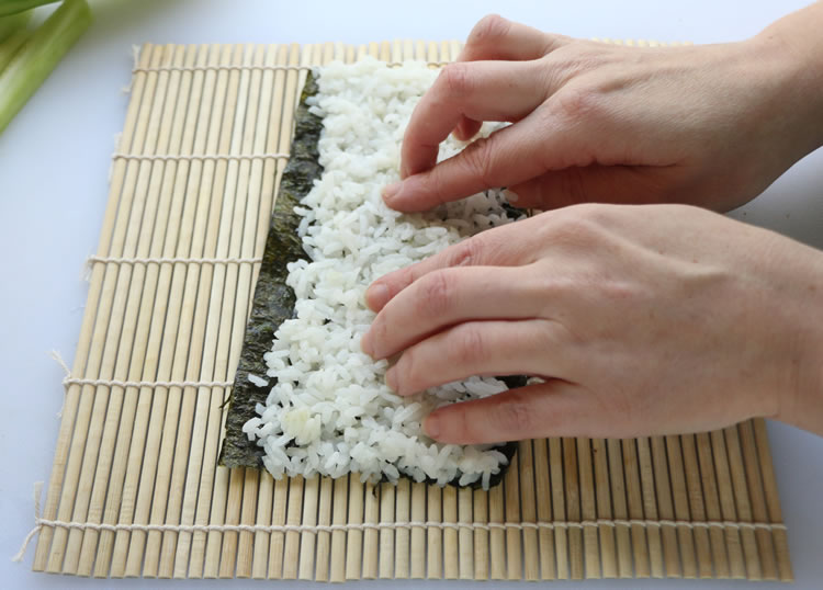 putting sushi rice on nori seaweed sheet