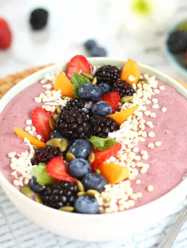 Mixed Berry and collagen peptide smoothie bowl topped with strawberries, blackberries, apricots, shredded coconut and pumpkin seeds.