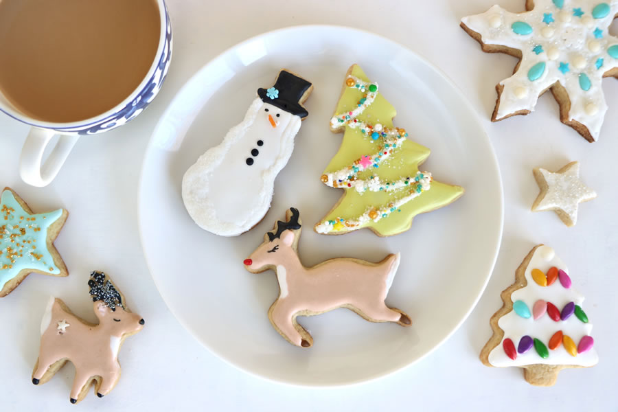 snowman christmas tree and reindeer sugar free sugar cookies on a plate made with stevia next to a cup of coffee