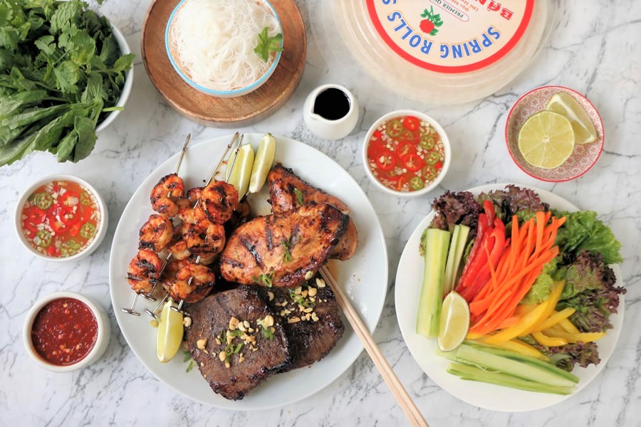 an overhead flatlay shot of a Vietnamese mixed grill with steak, chicken and shrimp served with veggies and herbs recipe