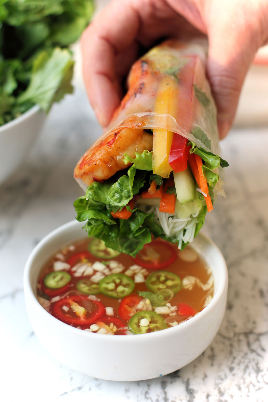 dipping Vietnamese spring rolls in a sweet and spicy sauce