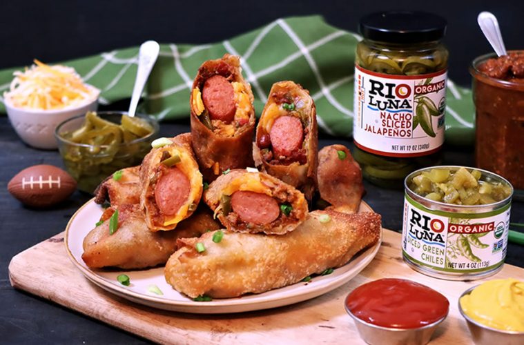 Chili Cheese Dog Egg Rolls Sliced on a plate with a mini foot ball ketchup mustard and Rio Luna Organic Nacho Sliced Jalapenos