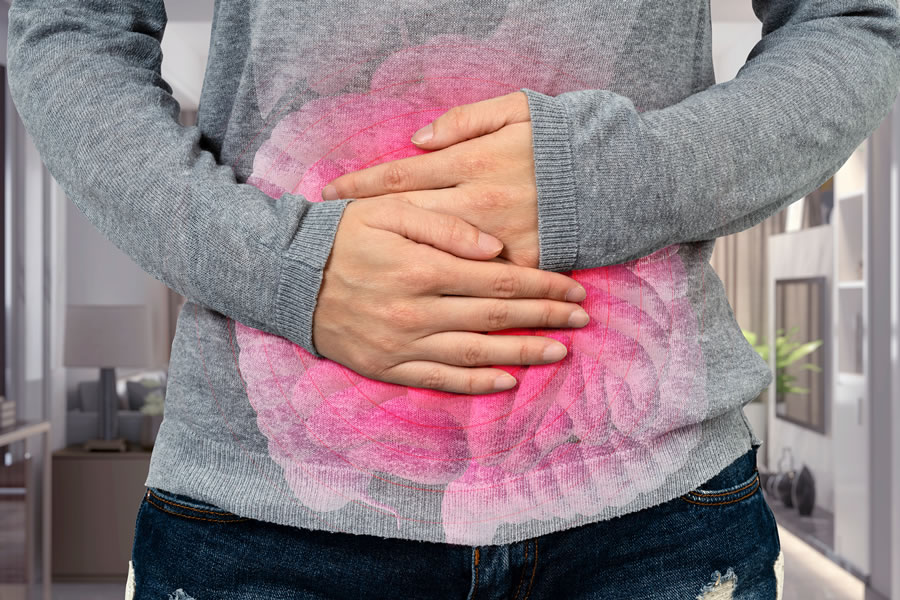 a woman in a gray sweater holding her stomach with a pink intestine overlayed