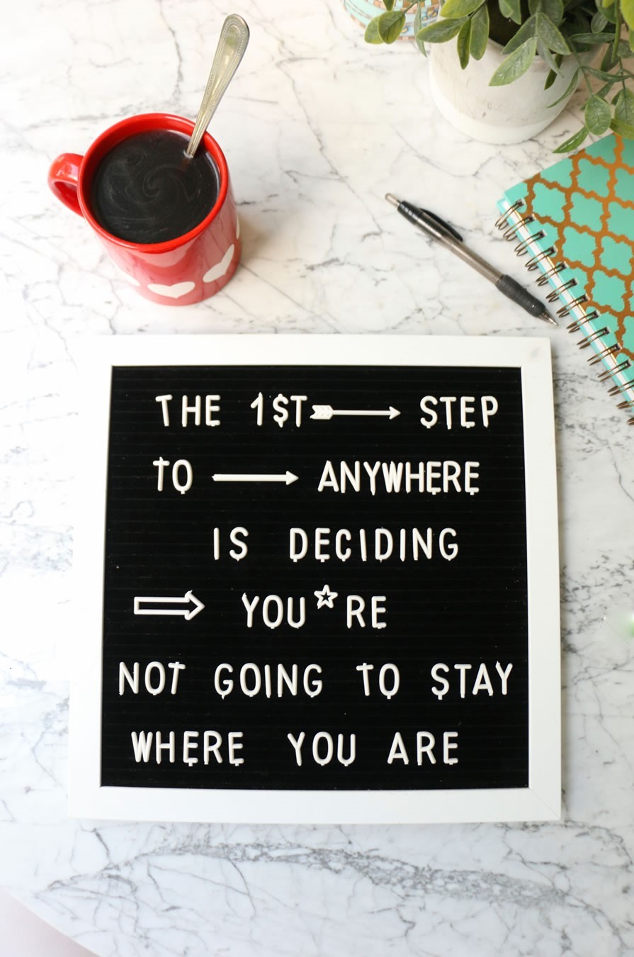 a letter board saying "The 1st Step To Anywhere Is Deciding You're Not Going To Stay Where You Are" next to a cup of coffee and journal motivational