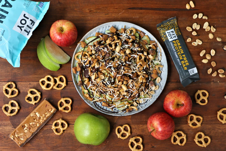 a plate of apple nachos made with grain-free FitJoy pretzels melted chocolate peanut butter toasted coconut