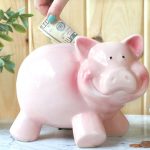 putting money in a pink piggy bank https://www.onbetterliving.com