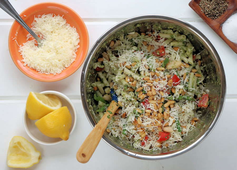 Stirring the pesto pasta ingredients in a big metal bowl