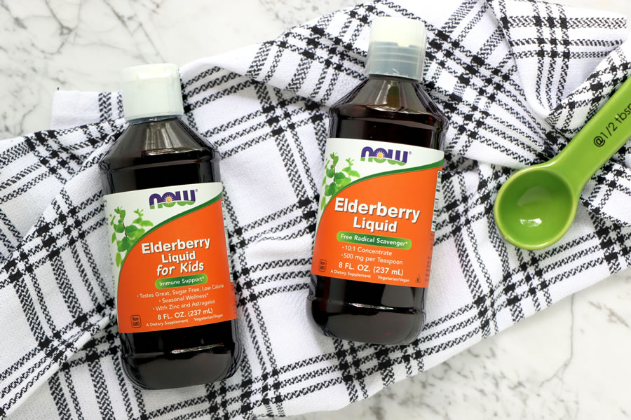 Now Foods Elderberry Liquid and Elderberry Liquid for kids on a black and white towel with a teaspoon