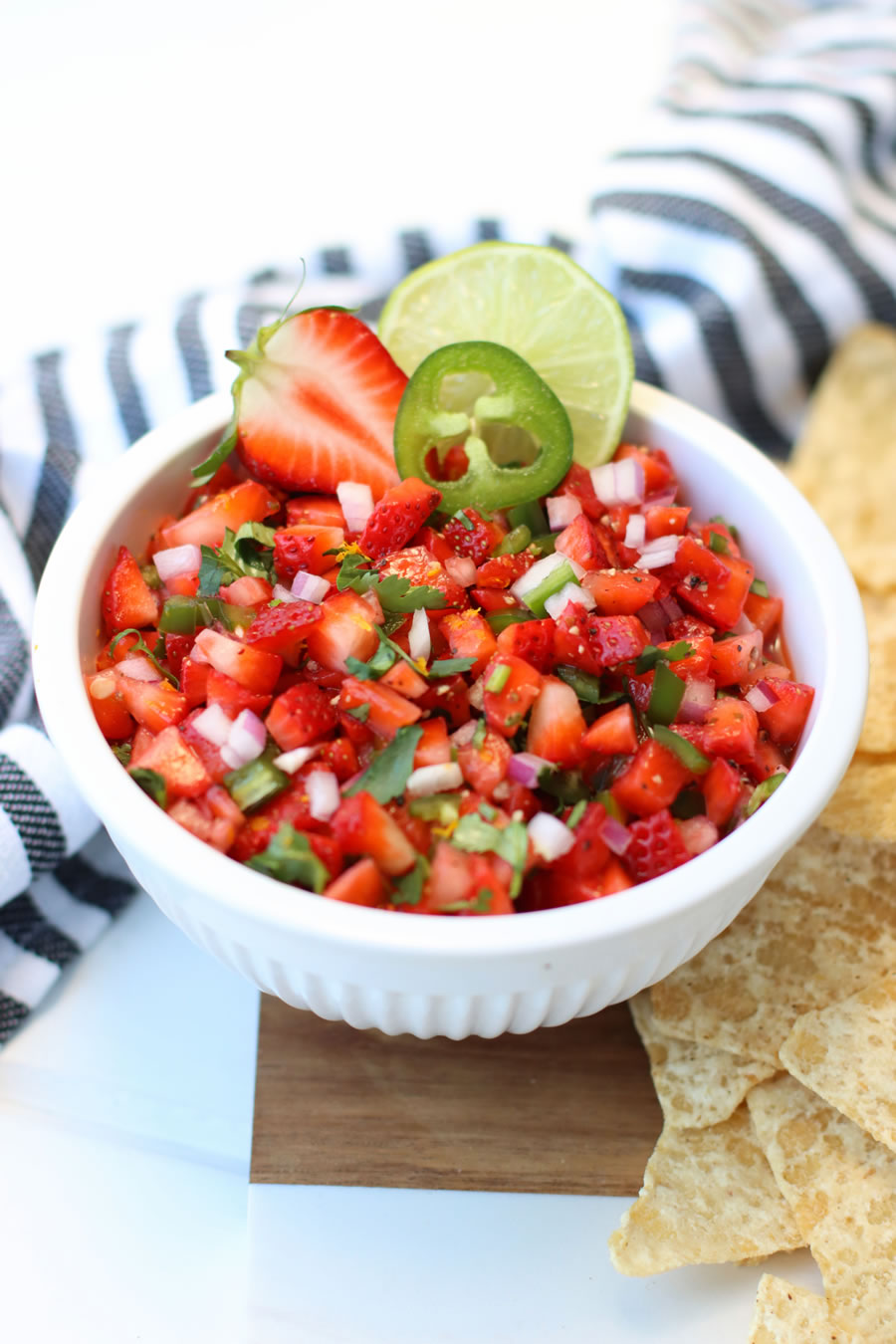 Strawberry Jalapeño Salsa in a white bowl next to a black and white striped napkin