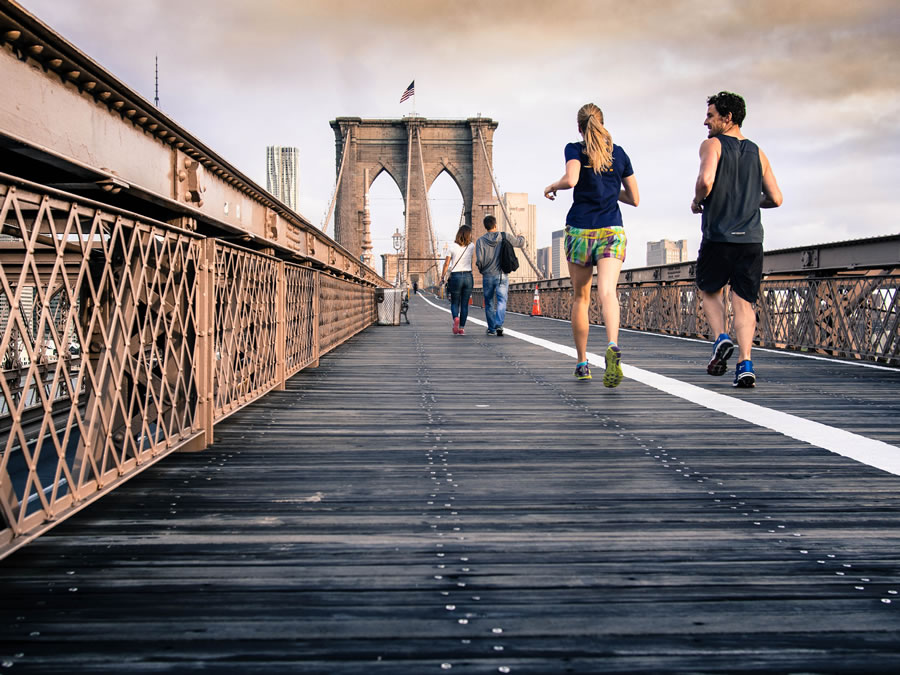 a couple jogging over a bridge