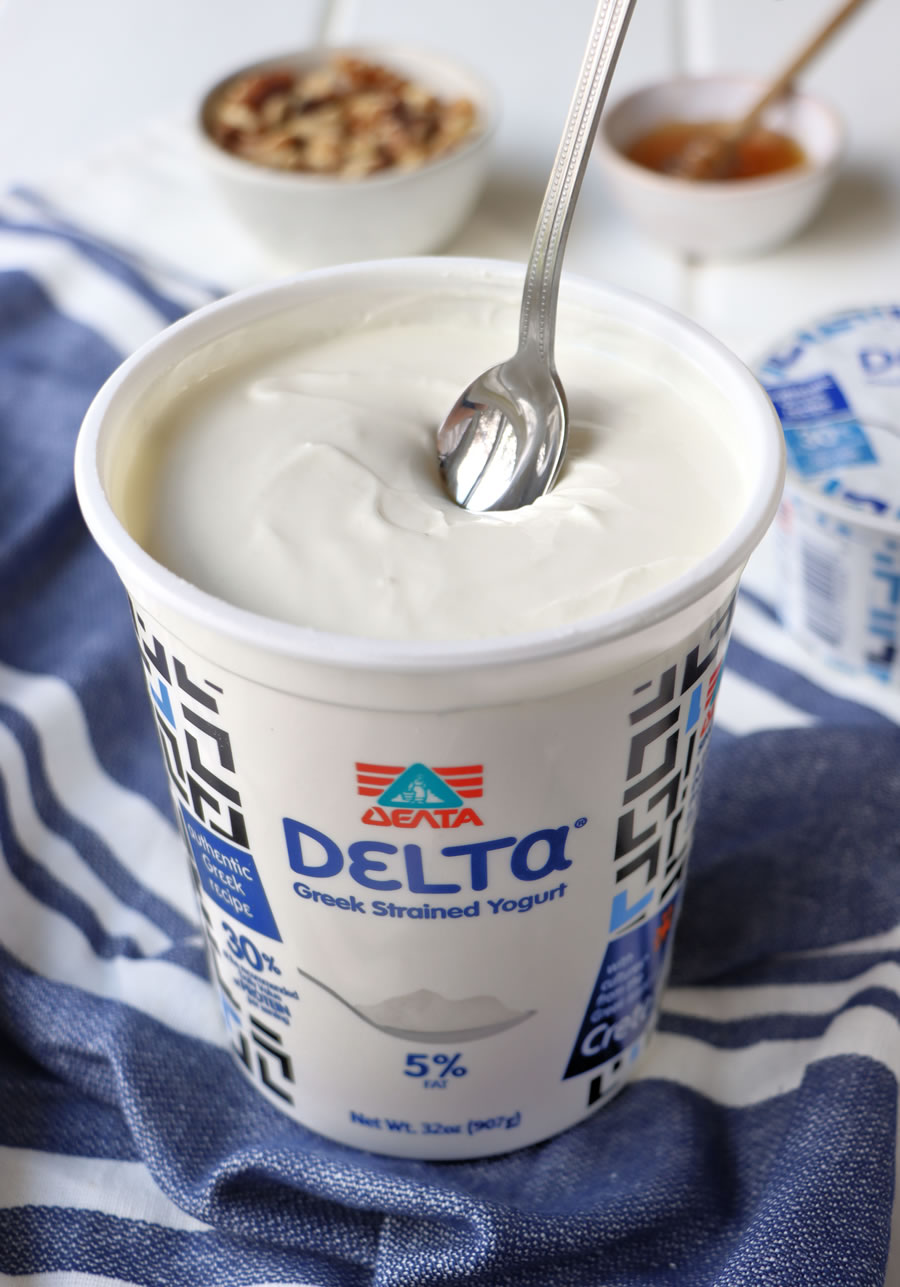 a spoon dipping into Delta Greek yogurt with walnuts and honey