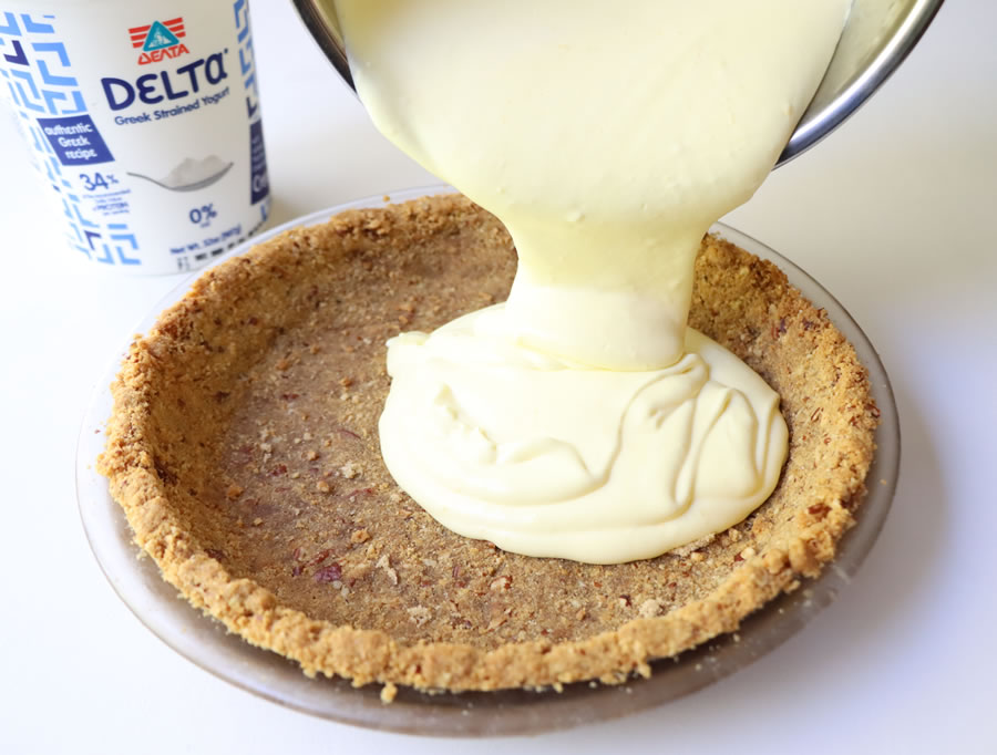 Pouring lemon cream pie filling made with Delta Greek Yogurt into a graham cracker crust