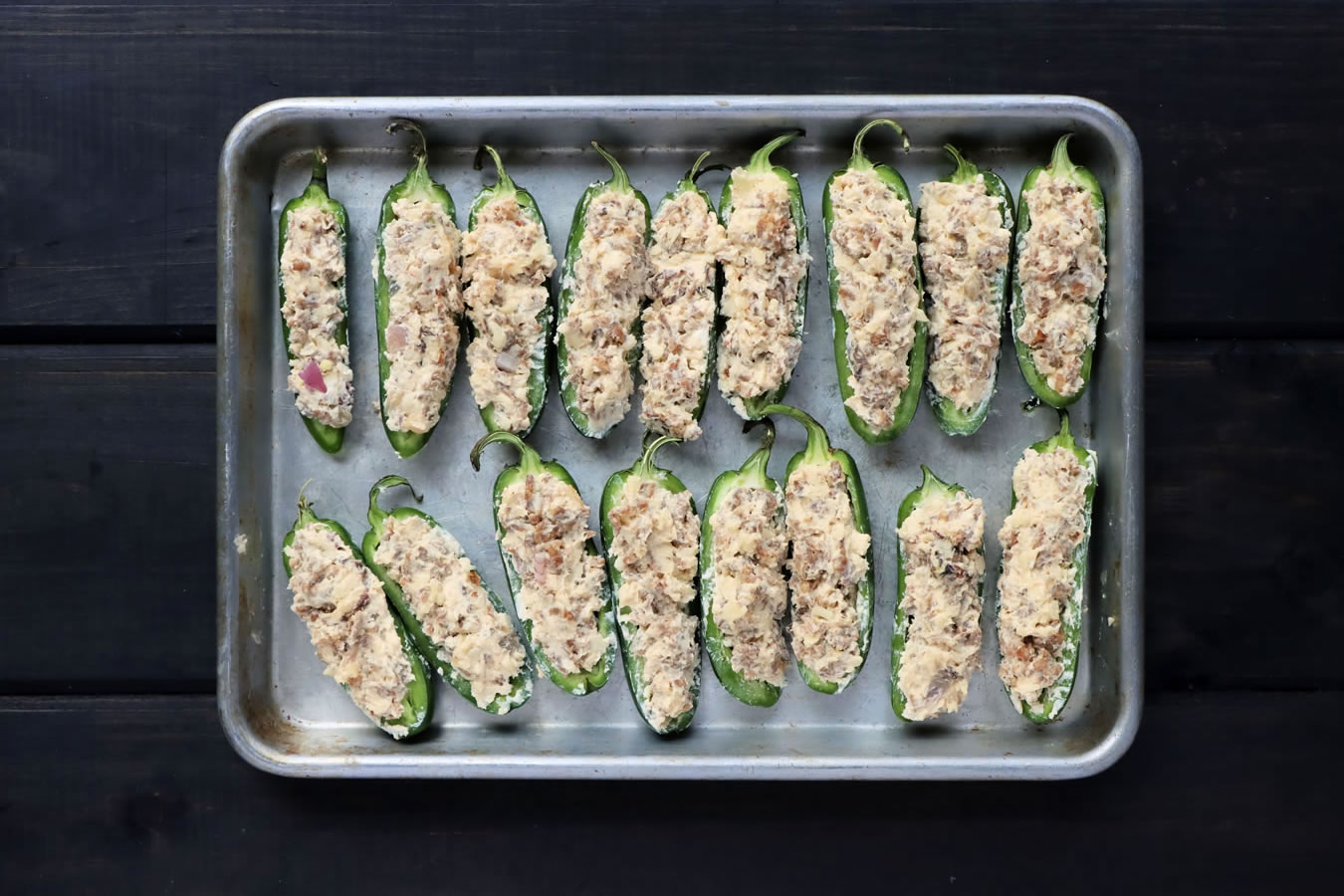 cheesy sausage stuffed Jalapenos on a baking sheet