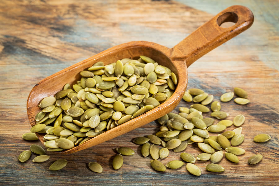 a wooden scoop of pumpkin seeds