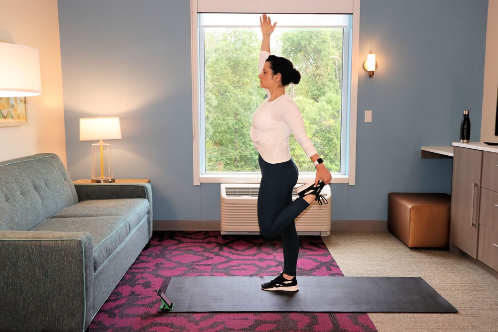 A woman is working out and doing yoga in a hotel room.