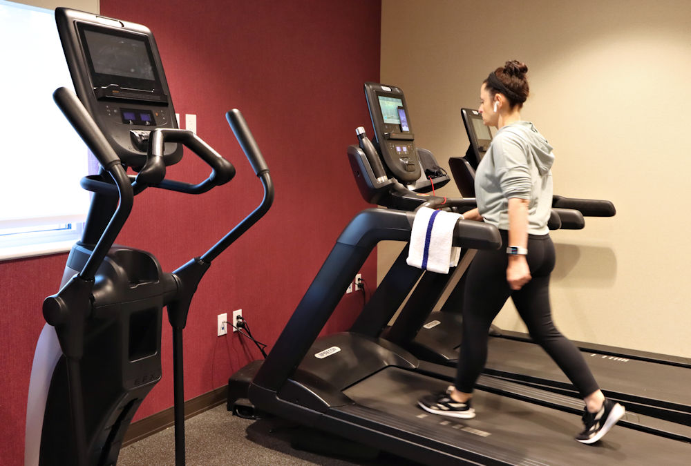 A woman walking on a treadmill in a gym.