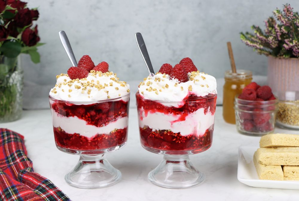 2 servings of authentic Scottish cranachan on a table with shortbread and ingredients.