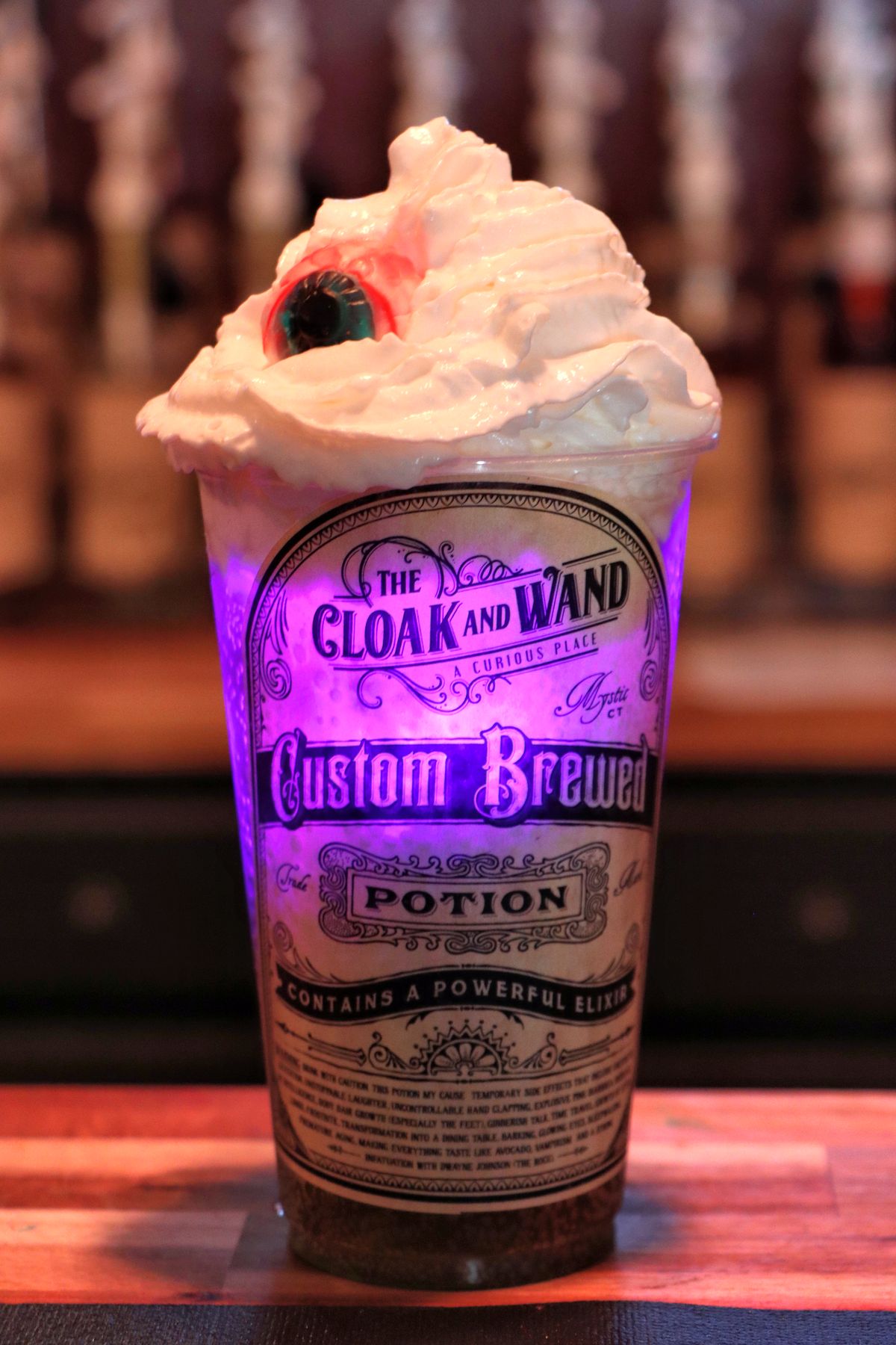 the black flame drink with flashing lights, whipped cream, and a candy eyeball from cloak and wand at peddlers village