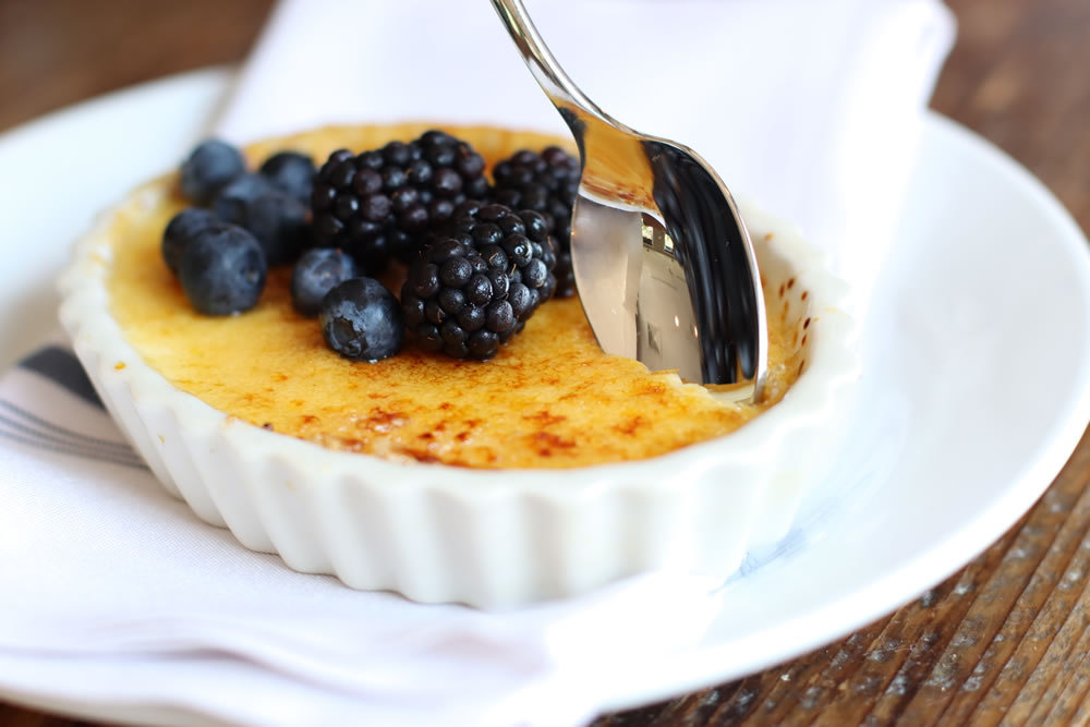 Creme Brulee with berries at Earl's New American at Peddler's Village. A spoon cracks the crisp crust.