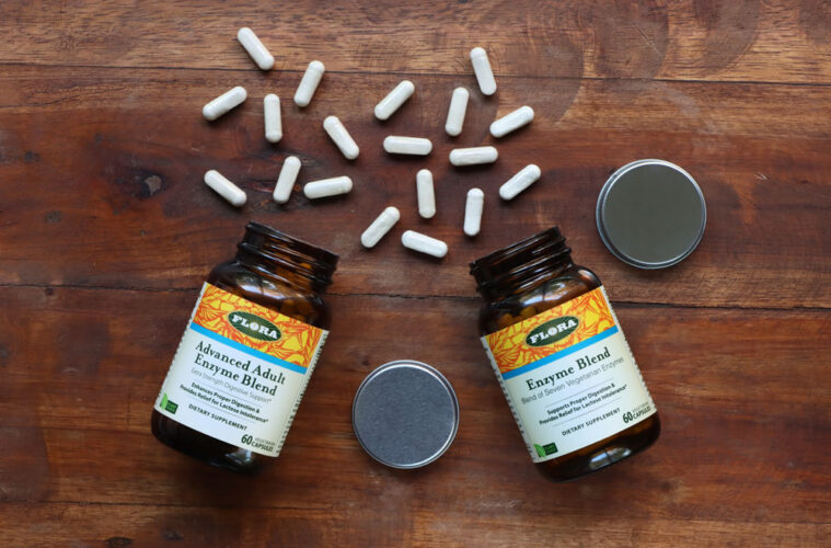 Advanced Adult Enzyme Blend and Enzyme Blend from Flora on a wooden table with capsules out.