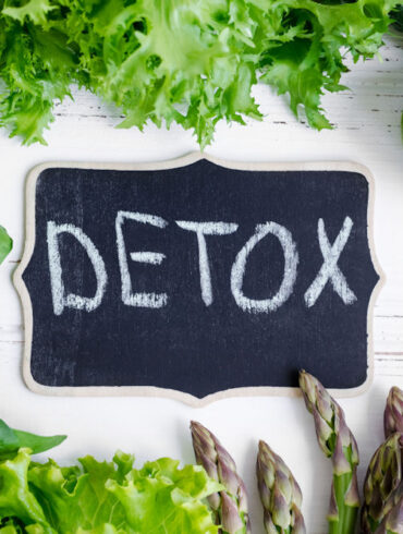 Detox written on a chalkboard surrounded by healthy ingredients.