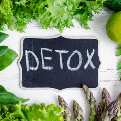 Detox written on a chalkboard surrounded by healthy ingredients.