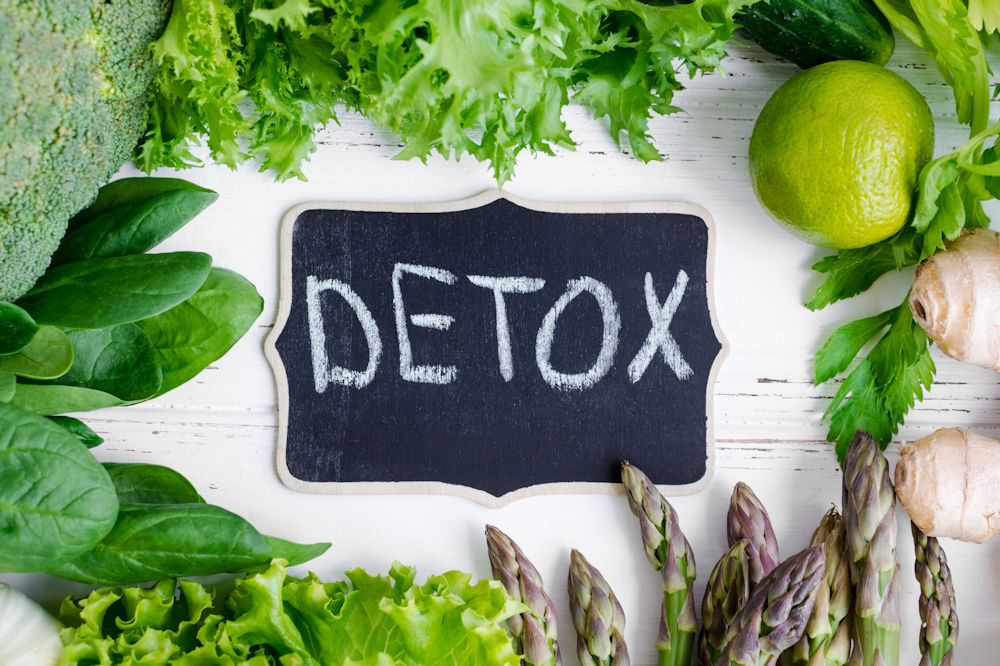 Detox written on a chalkboard surrounded by healthy ingredients.