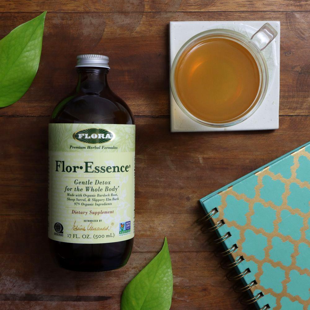 A bottle of Flor-Essence on a table with a mug and journal