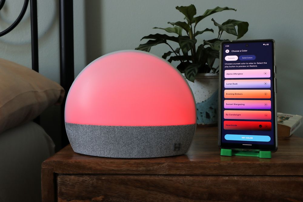 Hatch Restore and App on a nightstand at night with a pink sunset light. 