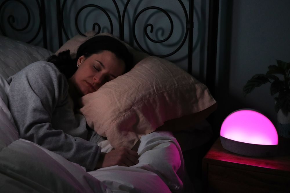 A woman sleeping and using the Hatch Restore nightlight and sound machine