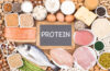 A selection of lean protein sources on a table including fish, chicken, eggs, tofu, legumes, and more.