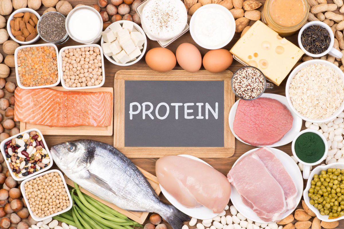 A selection of lean protein sources on a table including fish, chicken, eggs, tofu, legumes, and more.