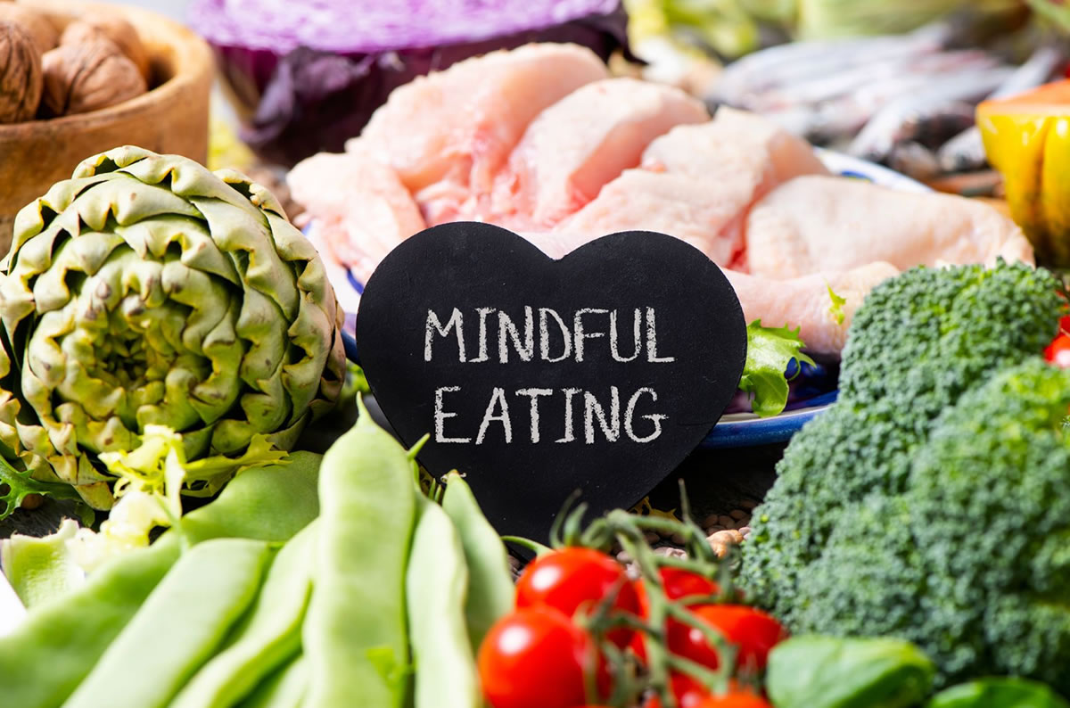 An assortment of healthy foods on a table with a heart shaped sign that reads "mindful eating"