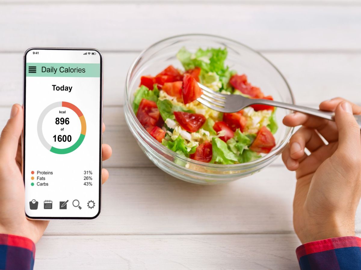 A person eating a salad and tracking it's calories with an app on a smartphone