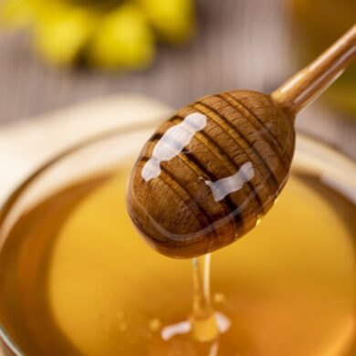 A jar of honey and honey dipper with honey on it.