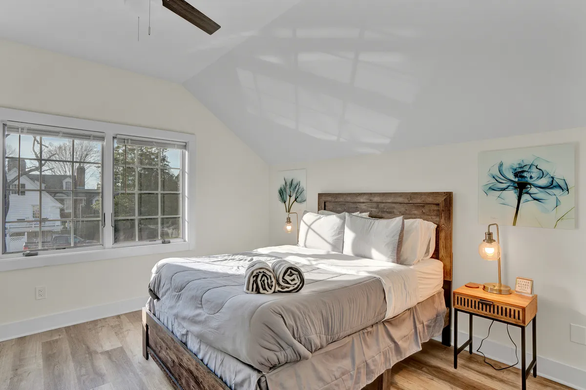 The cozy bedroom of the Carriage House Suite at Chimney Hill Estate with a queen bed, nightstands, artwork. 