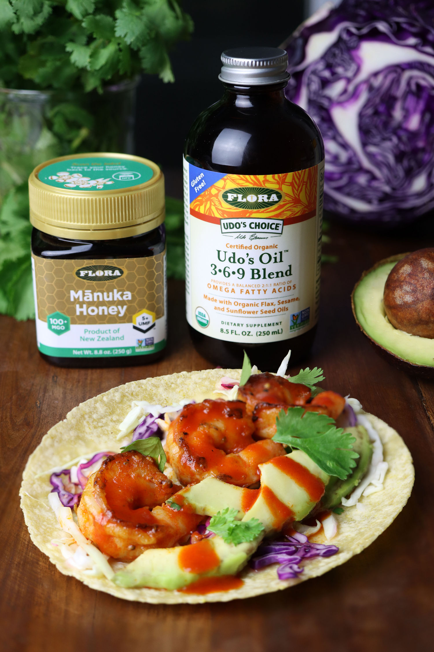 honey sriracha shrimp tacos in front of flora manuka honey and udos oil on a table with ingredients