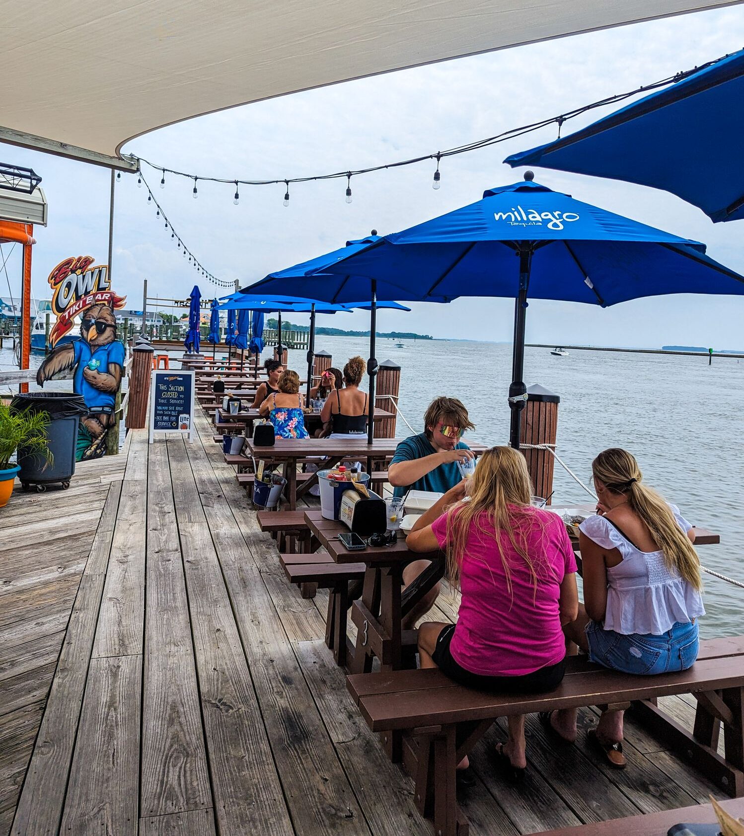 Customers dining and enjoying the outdoor deck on the water at Big Owl Tiki Bar.