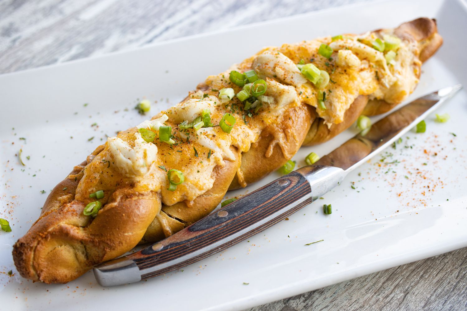 Dock House Crab Pretzel. Doughy braided pretzel topped with Creamy Crab Dip, cheddar cheese, scallions and a touch of Old Bay.