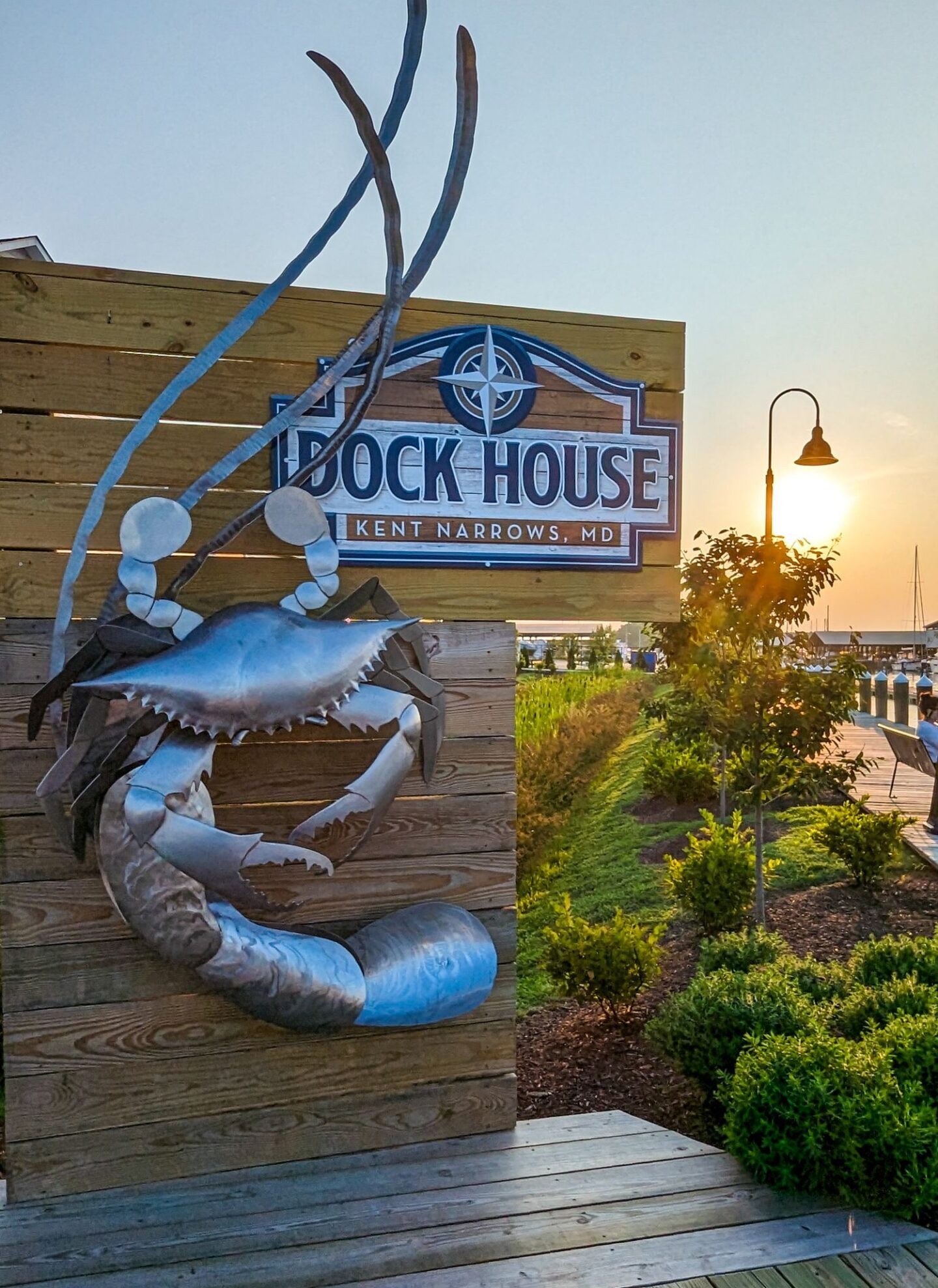 The front sign of Dock House restaurant with a giant blue crab on wood.