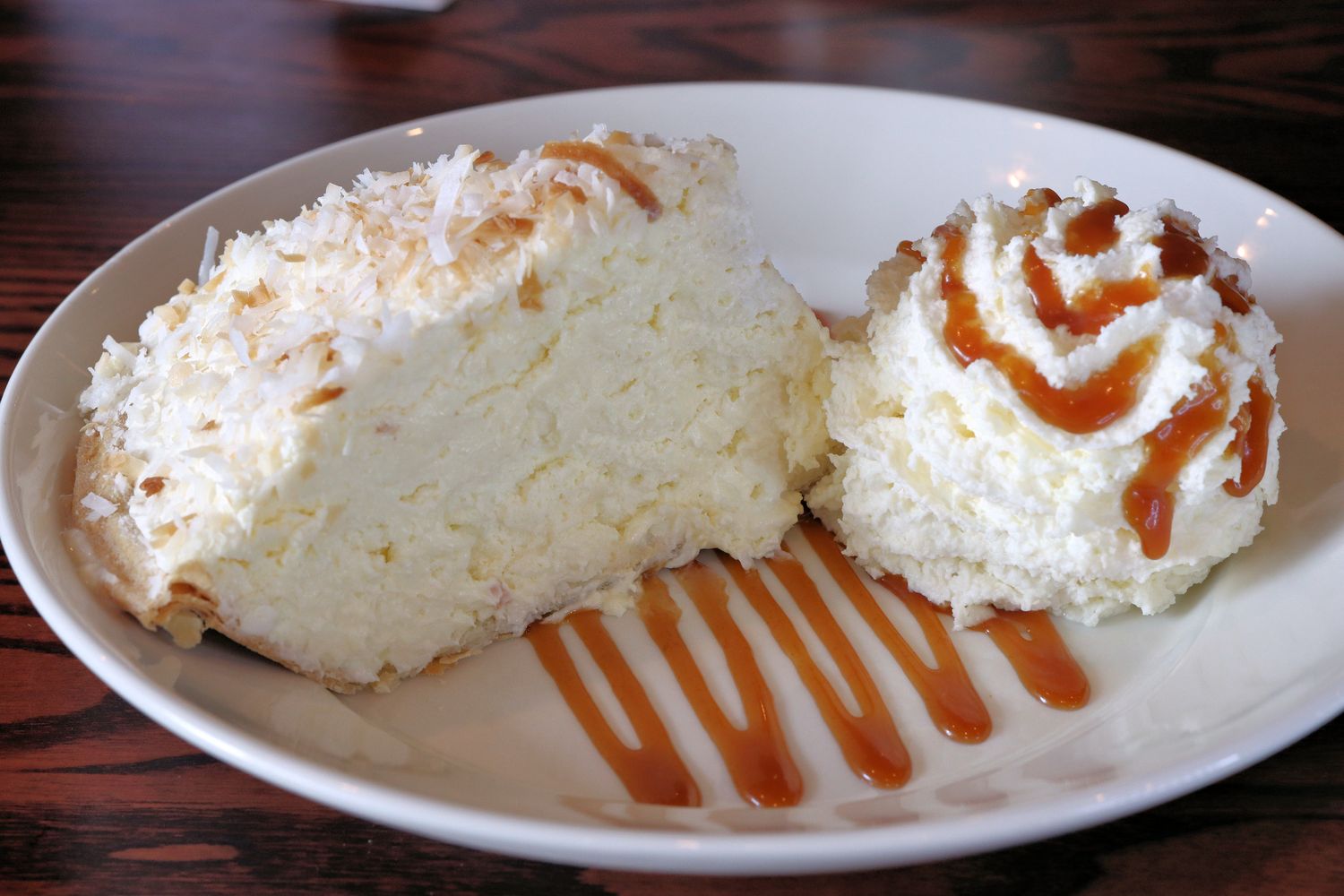 Coconut Cream Pie topped with whipped cream, salted caramel drizzle, and a sprinkle of toasted coconut.