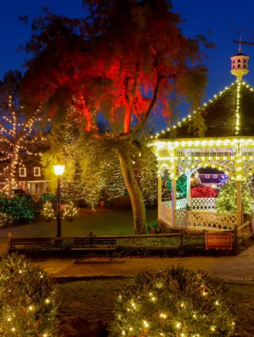 The gazebo at Peddler's Village lit up with Christmas lights at sunset.